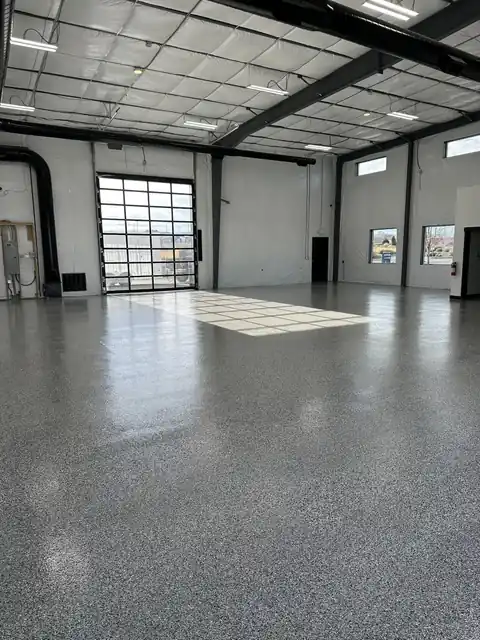 Large steel-framed shop with a glossy grey and white chip flake floor and a glass overhead door at the back