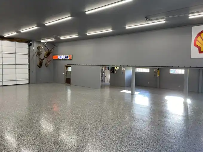 Finished glossy flake epoxy floor in the shop, ceiling lights reflecting along it