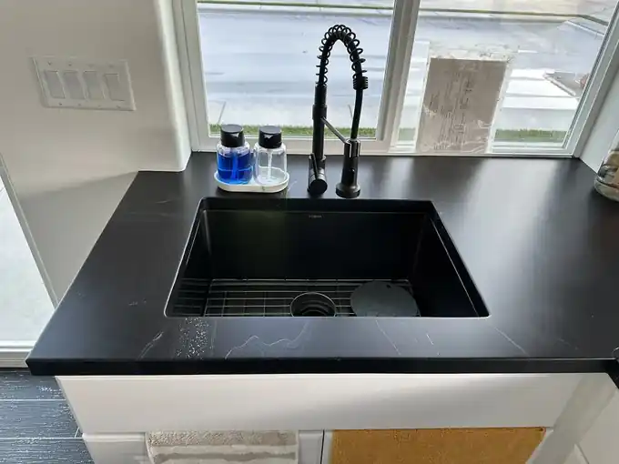 Black metallic epoxy countertop around an undermount sink with a black faucet