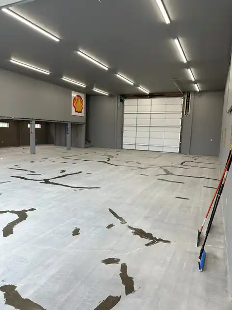 Shop floor slab with long cracks filled in dark repair material before coating