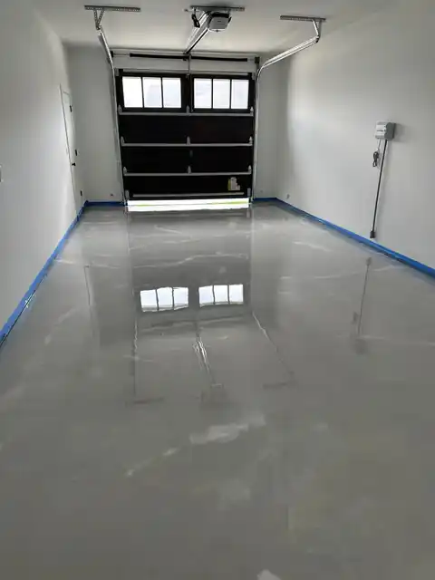 High-gloss solid grey epoxy floor in an empty garage reflecting the door windows