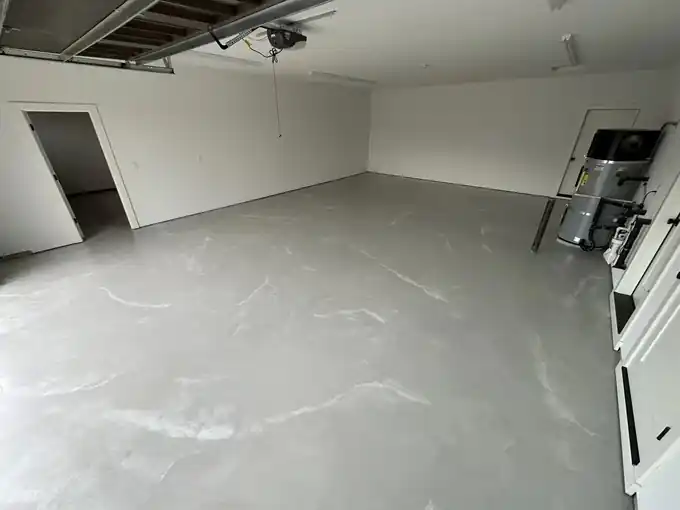Light grey epoxy floor in a two-car garage with a water heater against the back wall
