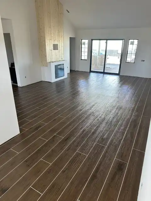 Dark brown plank-pattern floor running through an open living room toward sliding glass doors