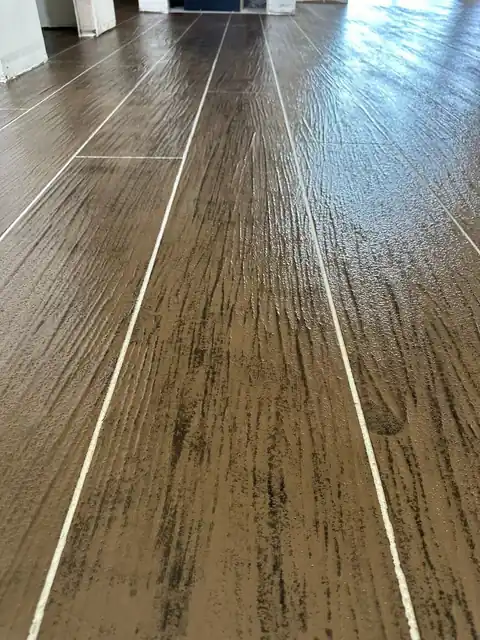 Close view of a brown plank pattern with pale grout lines and dark grain marks across the surface